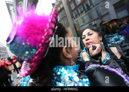 Mitglieder der bolivianischen Tanzgruppe tun ihr Make-up bei ihrer Vorbereitung auf die Londoner New Year Day Parade teilnehmen. Stockfoto