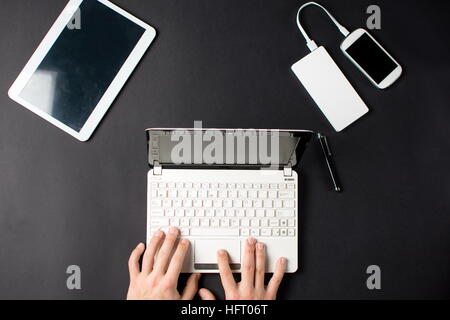 Mann, die Eingabe auf ein weißes Laptop auf schwarzem Hintergrund Stockfoto