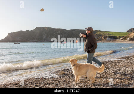 Mensch und Hund am Strand, die Felsen zu werfen, an einem sonnigen Wintertag spielen Stockfoto