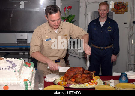 061123-N-0237L-016 Okinawa, Japan (23. November 2006) - USS Essex (LHD-2) Kommandierender Offizier, Captain Brian Donegan, schneidet einen Thanksgiving-Truthahn auf Schiffsdecks durcheinander als Essex' Supply Officer CMdR Carl Weiss blickt auf. Des Schiffs kulinarische Spezialisten gekocht 1.000 Pfund der ganzen Türkei, 1.000 Pfund der Türkei roll, 1.000 Pfund von Rib-Eye Rollen, 250 Pfund Schinken, 1.600 Pfund Brot dressing, 180 Pfund aus Kartoffelpüree, 60 Pfund Reis und 540 Pfund Süßkartoffeln für die eingeschifften Crew von fast 2.400 Segler und eingeschifften Elemente von der 31. Marine Expeditionary Unit (MEU) M Stockfoto