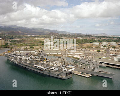 Aerial Quartal Hafenansicht der nuklear angetriebene Flugzeugträger USS ENTERPRISE (CVN-65) festgemacht in Pearl Harbor.  Vor Anker in der Nähe ist das schnell Kampfunterstützung Schiff USS SACRAMENTO (AOE 1) und die Lenkflugkörper Fregatte USS REID (FFG-30). USS Enterprise (CVN-65) in Pearl Harbor am 15. Juni 1984 Stockfoto