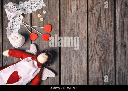 Engel ein Kuscheltier mit Herz, Spitzenband, Knöpfe und drei rote Herzen auf alten Holz Hintergrund. Valentine-Konzept. Ansicht von oben. Stockfoto