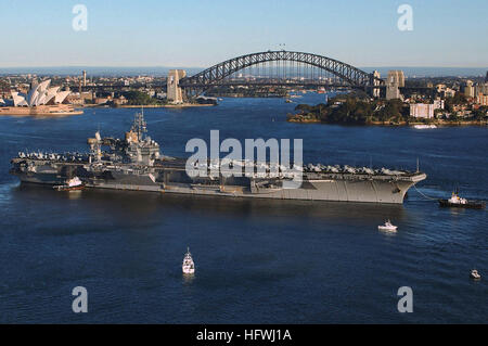 Steuerbordseite Blick auf die uns Navy (USN) Flugzeugträger USS KITTY HAWK (CV-63), wie es den Hafen von Sydney, Australien-Transite durch kommerzielle Schlepper unterstützt. Im Hintergrund sind die Sydney Opera House und Sydney Bay Bridge. Die KITTY HAWK hat nur Operationen im Rahmen der Übung TALISMAN SABRE 2005 abgeschlossen. (MINDERWERTIGE) USS Kitty Hawk (CV-63)-Sydney-Australien Stockfoto