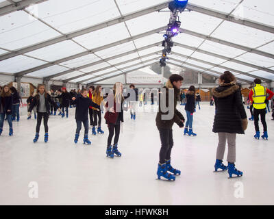 Menschen Sie Eislaufen auf der temporäre Eisbahn außerhalb Winchester Cathedral während der Weihnachtsmärkte. Stockfoto