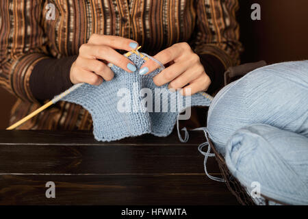 Weibliche Hände vom leichten blauen Garn stricken. Stockfoto