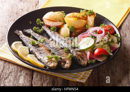 Gebratene Sardinen mit Bratkartoffeln und frischem Salat auf der Platte Nahaufnahme. horizontale Stockfoto