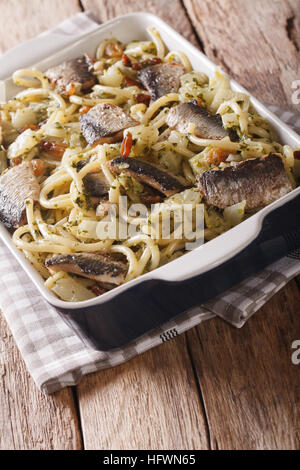 Italienische Küche: Pasta mit Sardinen, Fenchel, Rosinen und Pinienkernen hautnah in Auflaufform auf den Tisch. vertikale Stockfoto