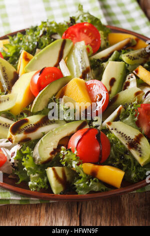 Frischer Salat von Mango, Avocado, Kiwi, Tomaten und Salat auf eine Platte Nahaufnahme. vertikale Stockfoto