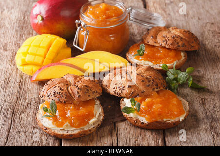 Brötchen mit Mango Marmelade, butter und mit Minze dekoriert hautnah auf dem Tisch. horizontale Stockfoto