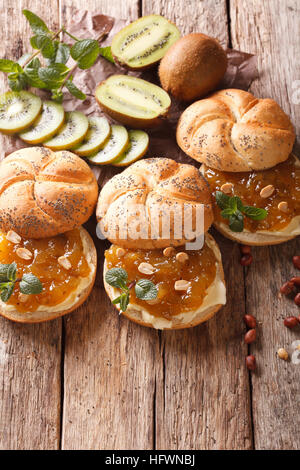 Süße Brötchen mit Butter, Kiwi Marmelade und Erdnuss close-up auf dem Tisch. Vertikal Stockfoto