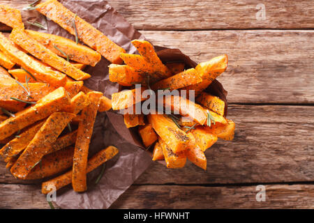 geröstete Süßkartoffeln mit Kräutern in einer Papier-Kegel-Großaufnahme auf dem Tisch. Horizontale Ansicht von oben Stockfoto