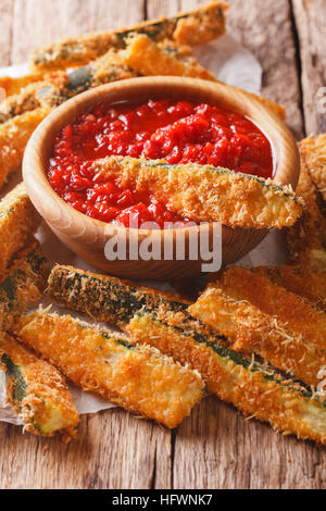 Gebratene Zucchini-Sticks paniert mit Parmesan und Tomaten Sauce Closeup auf einem Tisch. vertikale Stockfoto