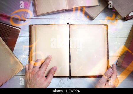 Alten Zauberbuch mit glühenden Tierkreissymbolen und Hand des Mannes zeigt wichtige Stelle. Leere Seite für Ihren text Stockfoto