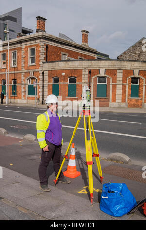 Surveyor bei Arbeit mit Messgeräten auf einem Stativ, North Wall Quay, Dublin Stockfoto