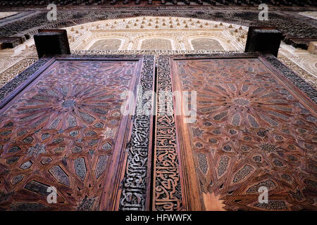 Die komplizierten Holztüren in der Bou Inania Madrasa in der Medina von Fes, Marokko umgeben von geschnitzten Verputz. Stockfoto