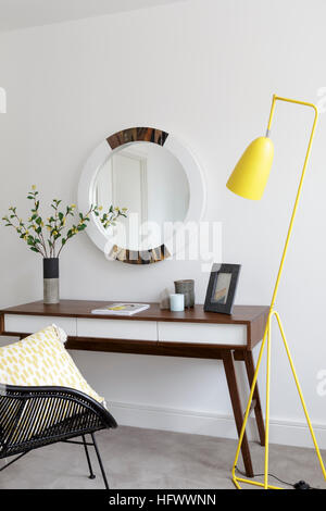 Schminktisch mit gelben Stehlampe und runder Spiegel Stockfoto