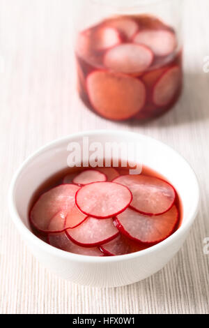 Frische Radieschen schneiden in dünne Scheiben geschnitten, eingelegt in Rotwein-Essig mit Zucker und Salz, mit Tageslicht fotografiert Stockfoto