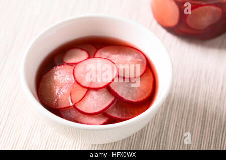 Frische Radieschen schneiden in dünne Scheiben geschnitten, eingelegt in Rotwein-Essig mit Zucker und Salz, mit Tageslicht fotografiert Stockfoto