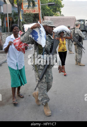 100131-N-6214F-020 PORT-AU-PRINCE, Haiti (31. Januar 2010) A Soldier zugewiesen der 82nd Airborne Division von Fort Bragg, N.C., mit Sitz in hilft einer Frau einen 55-lbs-Beutel Reis zu tragen, die sie von der World Health Organization an einem Lebensmittel-Vertrieb-Standort in Port-au-Prince, Haiti zu erhalten. Mehreren USA und internationale militärische und nicht-Regierungs-Organisationen führen humanitäre Hilfe und Katastrophenschutz Hilfsaktionen im Rahmen der Operation Unified Erleichterung nach eine Erdbeben der Stärke 7,0 schwere Schäden in und um Port-au-Prince, Haiti Jan. 12 verursacht. (U.S. Navy Photo von Chief Mass Communications Sp Stockfoto