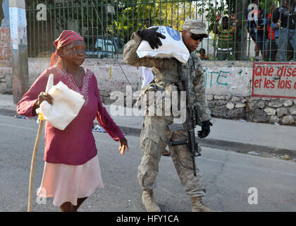 100131-N-6214F-035 PORT-AU-PRINCE, Haiti (31. Januar 2010) A Soldier zugewiesen der 82nd Airborne Division von Fort Bragg, N.C., mit Sitz in hilft einer Frau einen 55-lbs-Beutel Reis zu tragen, die sie von der World Health Organization an einem Lebensmittel-Vertrieb-Standort in Port-au-Prince, Haiti zu erhalten. Mehreren USA und internationale militärische und nicht-Regierungs-Organisationen führen humanitäre Hilfe und Katastrophenschutz Hilfsaktionen im Rahmen der Operation Unified Erleichterung nach eine Erdbeben der Stärke 7,0 schwere Schäden in und um Port-au-Prince, Haiti Jan. 12 verursacht. (U.S. Navy Photo von Chief Mass Communications Sp Stockfoto