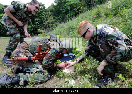 100521-N-8335D-722 SASEBO, Japan (21. Mai 2010) Krankenhaus Sanitätern beobachten Waffenwart 2. Klasse Wayne Nicholson behandeln medizinische Trainingspuppe unter simulierten Brand während einer tactical combat Casualty Care Übung. (Foto: U.S. Navy Mass Communication Specialist 1. Klasse Richard Doolin/freigegeben) US Navy 100521-N-8335D-722 Krankenhaus Sanitätern beobachten Waffenwart 2. Klasse Wayne Nicholson behandeln medizinische Trainingspuppe Stockfoto