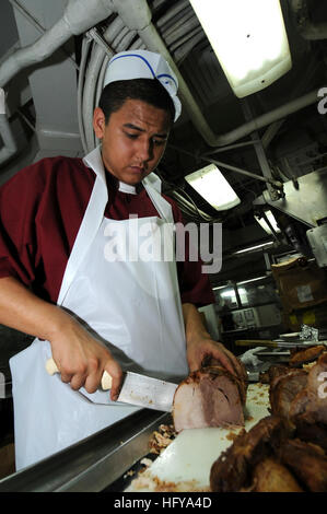 Der kulinarische Spezialist Seaman Apprentice bereitet Schweinebraten in der Achterküche an Bord des Flugzeugträgers USS George Washington (CVN 73) zu, der im westlichen Pazifik zur Unterstützung der regionalen Sicherheit und Stabilität eingesetzt wird. Stockfoto