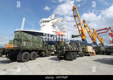 Ein Treibstofftanker des U.S. Marine Corps wird an Bord des MV Combi-Dock III befördert, während zusätzliche Fracht des Marine Corps auf dem Pier zum Verladen auf ein von der Military Sealift Command gechartertes Frachtschiff in der Subic Bay bereitgestellt wird. Stockfoto