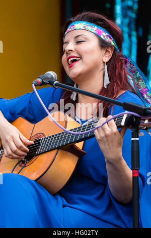 Kolumbianische Songwriter, Sänger und Gitarrist, Carolina Herrera in blauem Kleid, Gitarre spielen und Singen, während auf einer Open Air Bühne in Ramsgate. Stockfoto