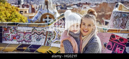 Barcelona-Handschrift. Porträt des Lächelns moderne Mutter und Tochter Touristen im Park Güell in Barcelona, Spanien zu umarmen, sitzend auf einer Bank Stockfoto