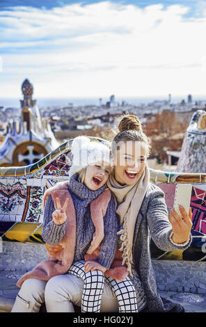 Barcelona-Handschrift. Porträt des Lächelns moderne Mutter und Tochter Reisende am Park Güell in Barcelona, Spanien mit dem Handy nehmen Selfie wh Stockfoto