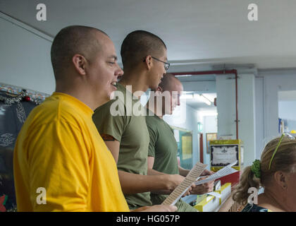 161121-N-LI768-101 Singapur (21. November 2016) von links, Petty Officer 1st Class Matt Eley, von Yreka, Calif., zugewiesen der amphibischen Angriff Schiff USS Makin Island (LHD 8), CPL Antwan Greer und Lance Cpl. Zachary Hamlin, die 11. Marine Expeditionary Unit (MEU) singen zusammen mit Studenten in der Genesis-Schule für Sonderpädagogik in einer Community Relations-Veranstaltung in Singapur zugewiesen.  Makin Island und eingeschifften 11. MEU durchgeführt, das Ereignis, um Matrosen und Marinesoldaten bieten die Möglichkeit, Singapurs Kultur zu erleben, wobei für die örtliche Gemeinschaft.  (U.S. Navy Photo von Petty Stockfoto