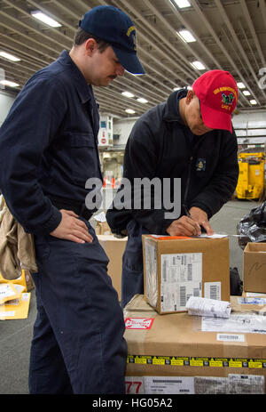 161128-N-XT039-081 SASEBO, Japan (28. November 2016) Chief Petty Officer Jerry Fababier (rechts), von San Diego, Anzeichen für das Sorgerecht für ein Paket von Seaman Jacobb Stene aus Sacremento, Kalifornien, während eine Teile-Abholung auf amphibischer Angriff Schiff USS Bonhomme Richard (LHD-6). Bonhomme Richard, vorwärts-bereitgestellt von Sasebo, Japan dient nach vorne schnellen Reaktionsfähigkeit im Falle einer regionalen Kontingenz oder Naturkatastrophe bieten. (Foto: U.S. Navy Petty Officer 3rd Class Jeanette Mullinax/freigegeben) USS Bonhomme Richard (LHD-6) S-8 Versorgung Teile-Abholung 161128-N-XT039-081 Stockfoto