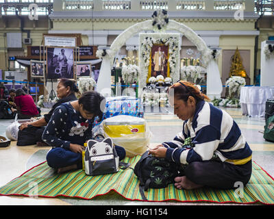 Bangkok, Bangkok, Thailand. 3. Januar 2017. Reisende sitzen auf dem Boden vor einem Porträt von Bhumibol Adulyadej, der spät König von Thailand, im Bahnhof Hua Lamphong in Bangkok. Reisende strömen in Bangkoks Bus- und Bahnstationen Dienstag, dem letzten Tag des langen Silvester Wochenende in Thailand. Zum Neujahrsfest in Thailand nennt man '' sieben tödlichen Tage '' aufgrund der Anzahl der tödlichen Autobahn und Verkehrsunfälle. Ab Montag Jan 2, 367 starben Menschen in Autobahn Unfälle über den Silvester-Urlaub in Thailand, ein Anstieg von 25,7 % gegenüber dem gleichen Zeitraum im Jahr 2016. (Kredit-Bild: © Stockfoto