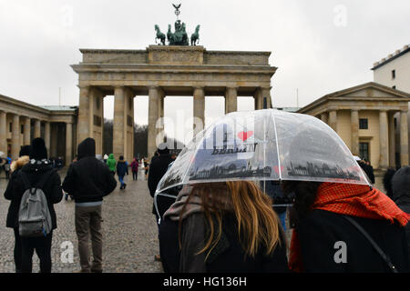 Berlin, Deutschland. 3. Januar 2017. Italienische Touristen schützen sich mit einem Regenschirm vor dem Regen am Brandenburger Tor in Berlin, Deutschland, 3. Januar 2017. Foto: Maurizio Gambarini/Dpa/Alamy Live News Stockfoto