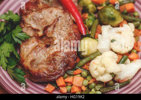 Gegrilltes Steak mit Gemüse und Kräutern auf Platte Stockfoto