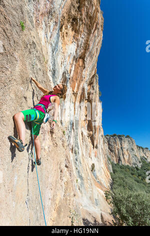 Jolly Young Girl an vertikale Wand sonnigen Felslandschaft hängen Stockfoto