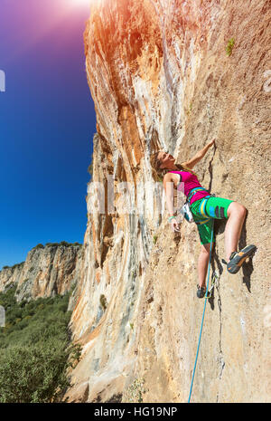 Jolly Young Girl an vertikale Wand sonnigen Felslandschaft hängen Stockfoto