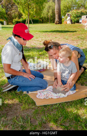 Ein Junge lernt alten indianischen Stein Korn Schleifen aus freiwilliger bei einem "Frühen Kalifornien Tage" Festival in einem Park in Costa Mesa, CA. Stockfoto