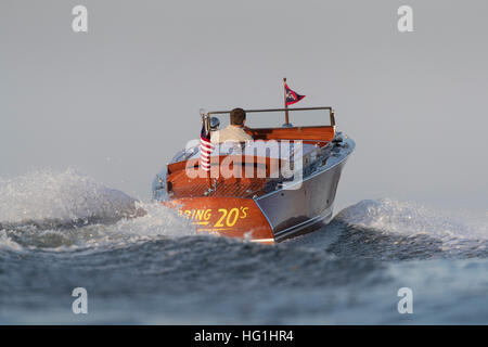 Ein Mann, der in einem antiken Chris-Craft-Schnellboot davonfährt. Stockfoto