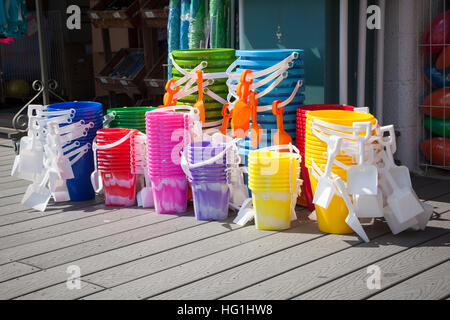 Stapel von bunten Strand Eimer sitzen vor einer Promenade laden zum Verkauf. Stockfoto