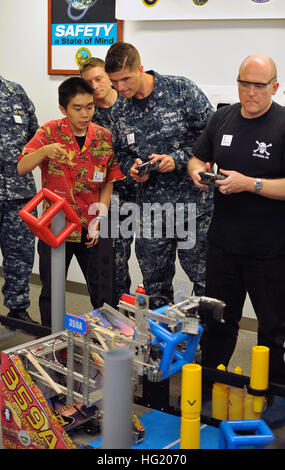 Yoshio Yoshizumi, Senior an der Waialua High School beauftragt Elektroniker / 3. Klasse Joel Reed von USS Cape St. George (CG-71) in der Pilotierung des Waialua Teams Roboter während eines High-School-Robotik-Wettbewerbs in der Pearl Harbor Naval Shipyard statt. Der Roboter war einer der mehrere Einträge in der Felge der Pazifik (RIMPAC) Übung 2014 Robotics Wettbewerb gesponsert von der US-Pazifikflotte und das Office of Naval Research. Zeigen Sie ihre Einträge, Studenten hatte eine Chance zu treffen RIMPAC Teilnehmer und Geläufigkeit in Wissenschaft, Technologie, Technik und Mathematik (STEM) Fähigkeiten. Twen Stockfoto