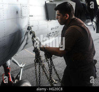 Airman Thomas Fuller, ein Victorville, Kalifornien, Native zugewiesen, die "Bluehawks" der Hubschrauber Maritime Strike Squadron (HSM) 78, klinkt sich einen Haken auf eine MH-60R Sea Hawk an Bord des Flugzeugträgers USS Ronald Reagan (CVN-76). Ronald Reagan beteiligt sich am Rand des Pazifik (RIMPAC) Übung 2014. Zweiundzwanzig Nationen, mehr als 40 Schiffe und sechs u-Boote, mehr als 200 Flugzeugen und 25.000 Mitarbeiter beteiligen sich an RIMPAC Übung vom 26. Juni bis Aug. 1, in und um die Inseln von Hawaii. Der weltweit größte internationale maritime Übung RIMPAC bietet eine einzigartige Trainingsmöglichkeit Stockfoto