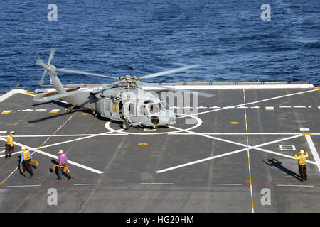 Luftfahrt Bootsmännern Mate Airman Tyler Bayne leitet Matrosen an Bord amphibious Transport dock-Schiff, die USS Green Bay (LPD 20) einziehen zu ersticken und Kette ein MH-60 s Sea Hawk Hubschrauber Helikopter Meer Combat-Geschwader 3 zugeordnet. Die Crew von Green Bay ist derzeit in der Phase des Basic Training in Vorbereitung auf vorwärts Bereitstellung nach Sasebo, Japan Anfang nächsten Jahres. (Foto: U.S. Navy Mass Communication Specialist 1. Klasse Elizabeth Merriam/freigegeben) USS Green Bay Flugbetrieb 140730-N-BB534-236 Stockfoto