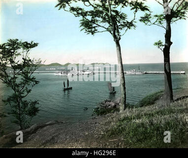 US-Kriegsschiffe, darunter die USS Black Hawk (AD-9), vier Zerstörer, die USS Whipple (DD-217) und die USS Heron (AM-10), sind in den späten 1930er Jahren innerhalb und außerhalb eines Wellenbrechers bei Chefoo positioniert, wobei die Amphibienflugzeuge der Grumman JF auf dem Fantail und im Wasser stehen. Chinesische Sampane segeln im Vordergrund. Stockfoto