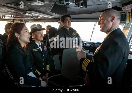 151018-N-IN729-169 Gewässer südlich von JAPAN (18. Oktober 2015) Captain Christopher Bolt, Recht, Kommandierender Offizier der US Navy nur vorwärts bereitgestellt Flugzeugträger USS Ronald Reagan (CVN-76), erklärt Flugdeck Operationen, der japanische Premierminister Shinzo Abe, Center, bei einem Besuch in das Schiff. Ronald Reagan und der eingeschifften Geschwader Carrier Air Wing (CVW) 5, bieten eine kampfbereit Kraft, die schützt und verteidigt die kollektive maritime Interessen der USA und ihrer Verbündeten und Partner in der Indo-Asien-Pazifik-Region. (Foto: U.S. Navy Mass Communication Specialist 3. Klasse Ryan McFarl Stockfoto