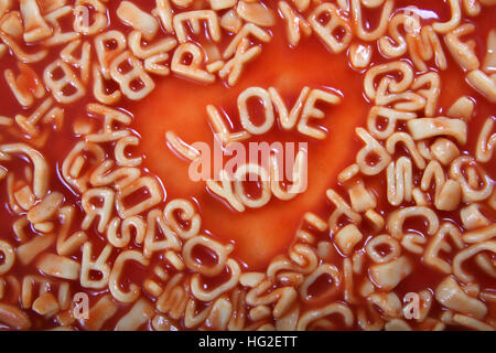 Ich liebe dich Text geschrieben in Alphabetti Spaghetti Nudeln geformt Briefe mit Tomatensauce um ihn herum. Stockfoto