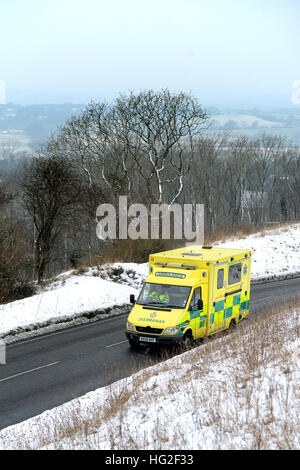 Krankenwagen auf einer Landstraße, umgeben von Schnee im Winter. Stockfoto