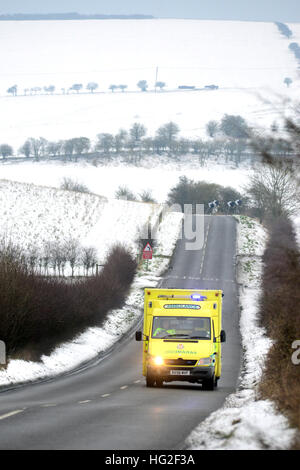 Krankenwagen auf einer Landstraße, umgeben von Schnee im Winter. Stockfoto