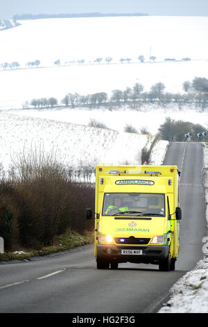 Krankenwagen auf einer Landstraße, umgeben von Schnee im Winter. Stockfoto