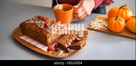 Bereit, in eine schöne, heiße Tasse reichen Tee, begleitet von frisch gebackenen, hausgemachte Kürbis-Brot mit Preiselbeeren und Kürbiskernen einzutauchen. Auf einem hölzernen Stockfoto